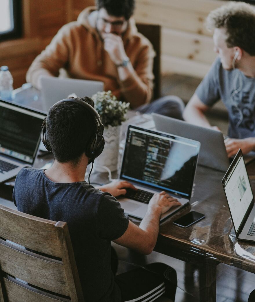 A team of developers working together on laptops around a shared table